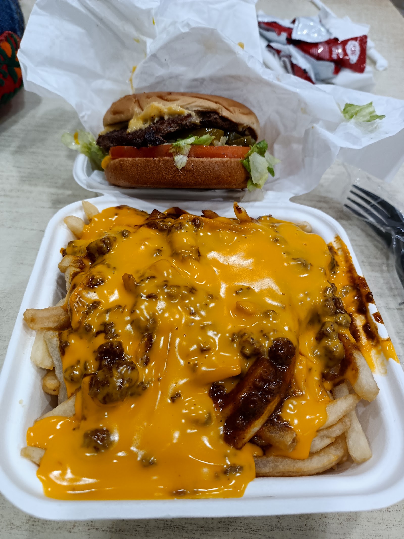 Chili cheese fries piled high next to a chili dog, ready to go